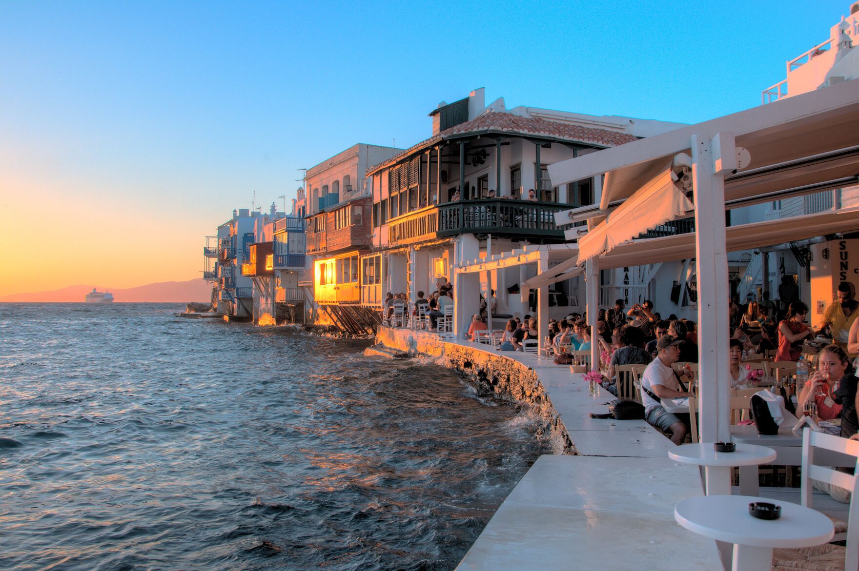 Little Venice, Mykonos, at sunset — waterfront cafes lit up over the Aegean